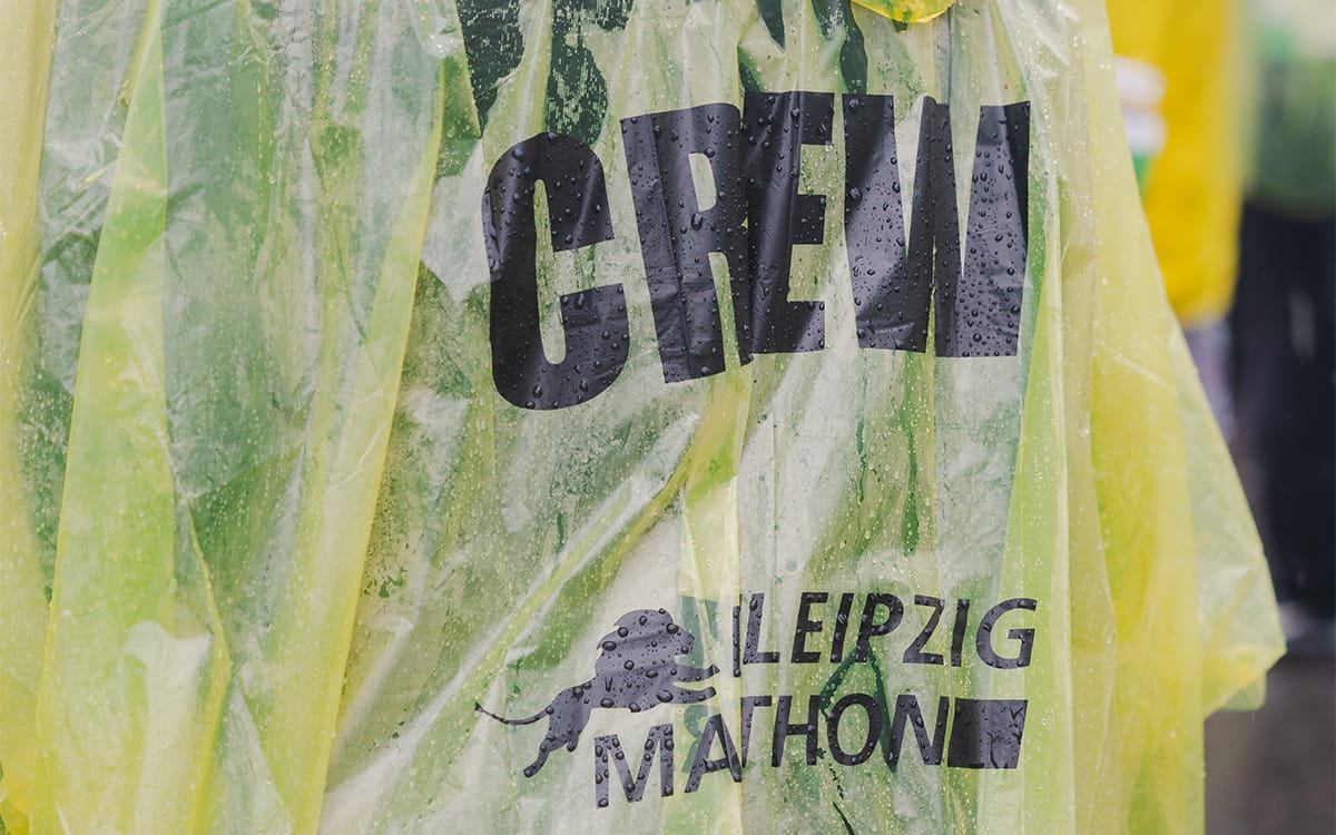Person mit gelbem Regencape mit dem Leipzig Marathon Logo